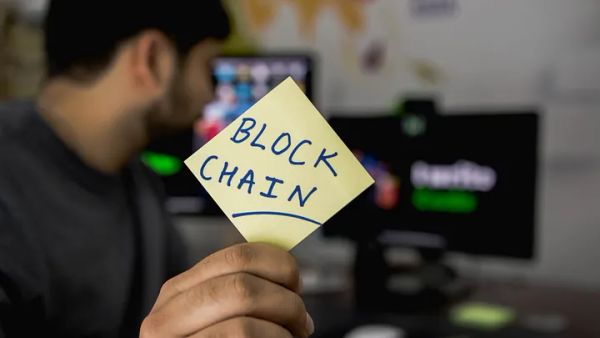 A man holding out a post-it note saying "block chain"