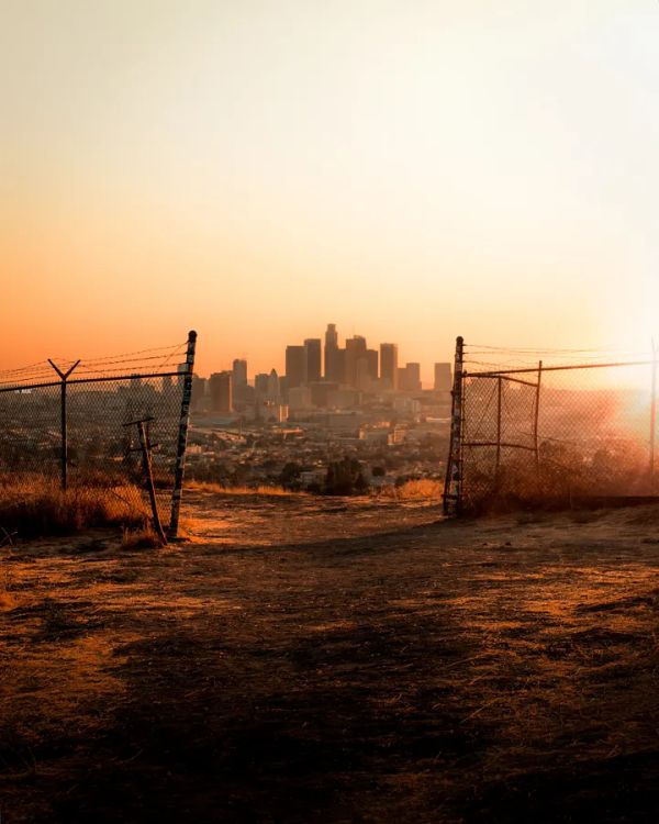 A city far away in a dusky lighting. Rusty fence with barbed wire on the foreground.